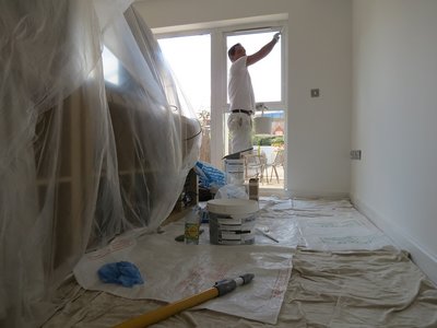 Residential painting in Clerkenwell. Lounge painted in white with dustsheets on floor and furniture