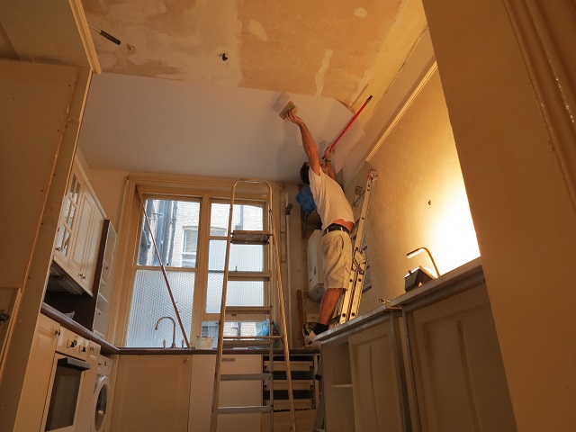 Painter in central London filling and lining a ceiling with ladders