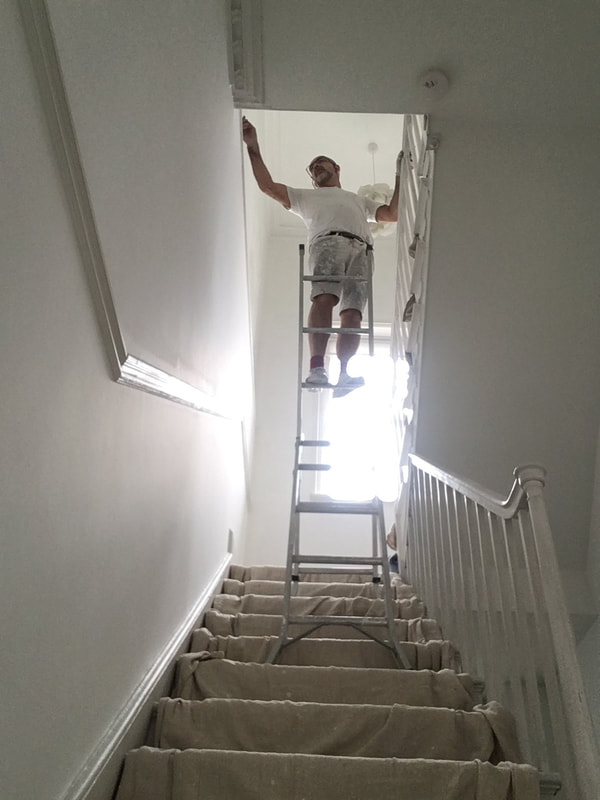 Painter in London up a ladder painting a stairway