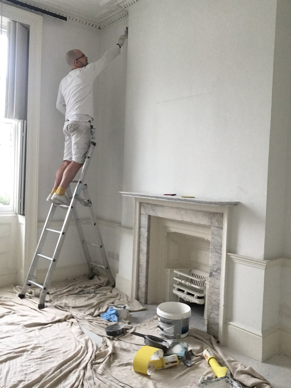 Painter decorator up a step ladder painting in Central London